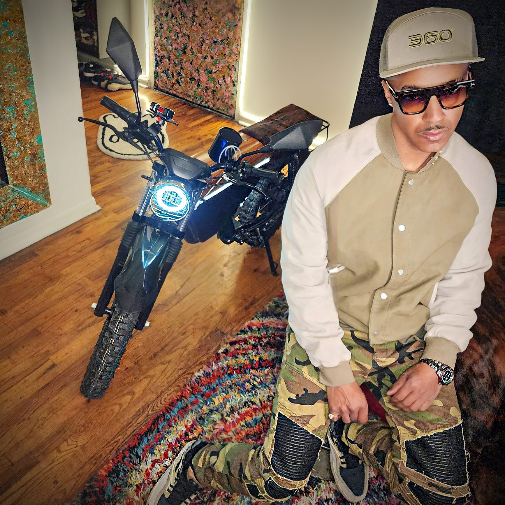 Vaughn Lowery pens e-bike review for ONYX Motorbikes RCR for 360 MAGAZINE, wearing Tom Ford eyewear, Allsaints jacket, and Reebok sneakers.